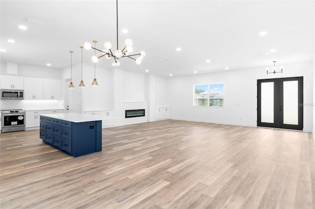 unfurnished living room featuring a chandelier, a large fireplace, and light wood-style flooring