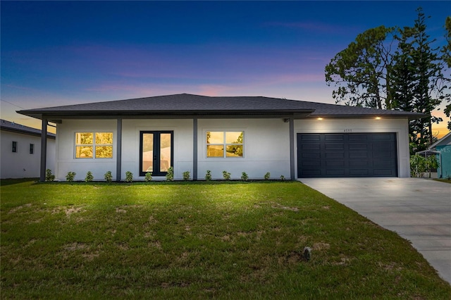 view of front facade with an attached garage, a shingled roof, a yard, driveway, and stucco siding