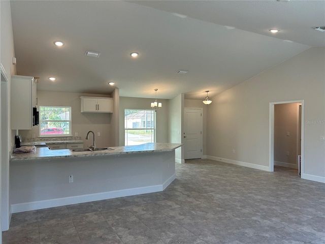 kitchen with hanging light fixtures, vaulted ceiling, a healthy amount of sunlight, and white cabinets