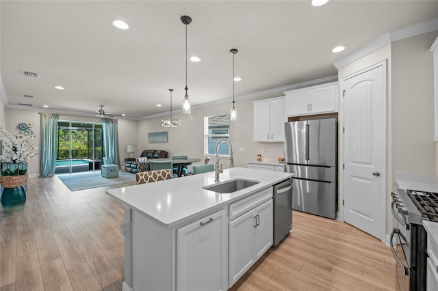 kitchen featuring stainless steel appliances, white cabinetry, a kitchen island with sink, and sink