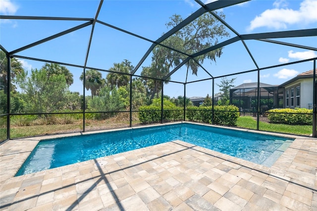 view of pool with glass enclosure and a patio area