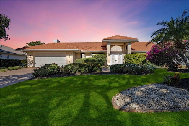 mediterranean / spanish house featuring a yard and a garage