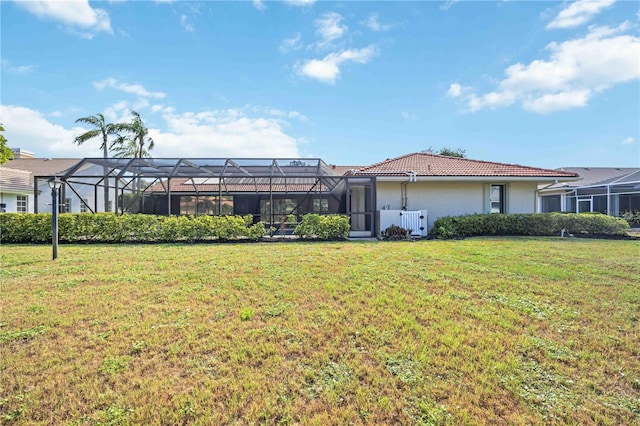 back of property featuring a lanai and a lawn