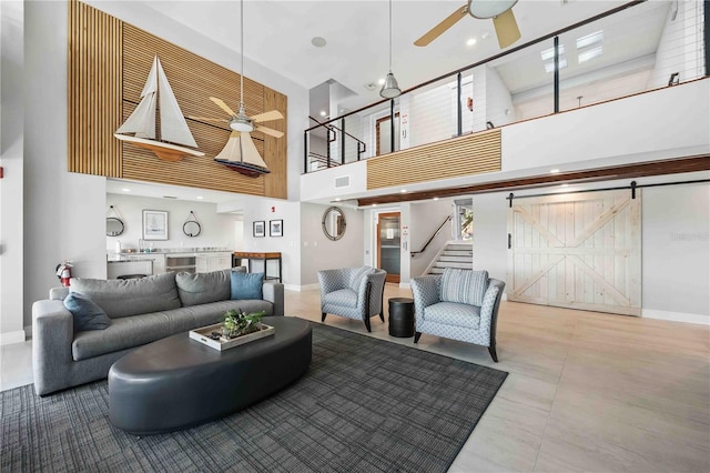 living room featuring a high ceiling, ceiling fan, a barn door, and sink