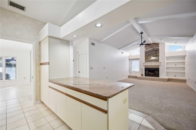 kitchen with light carpet, lofted ceiling with beams, ceiling fan, a wealth of natural light, and white cabinets