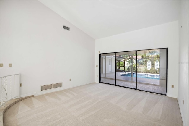 carpeted empty room featuring high vaulted ceiling