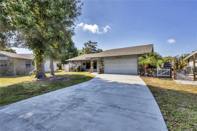 ranch-style home with a front lawn, central AC unit, and a garage