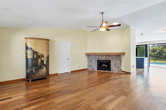 unfurnished living room featuring ceiling fan, a fireplace, wood-type flooring, and vaulted ceiling