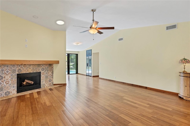 unfurnished living room featuring ceiling fan, vaulted ceiling, a fireplace, and light hardwood / wood-style flooring