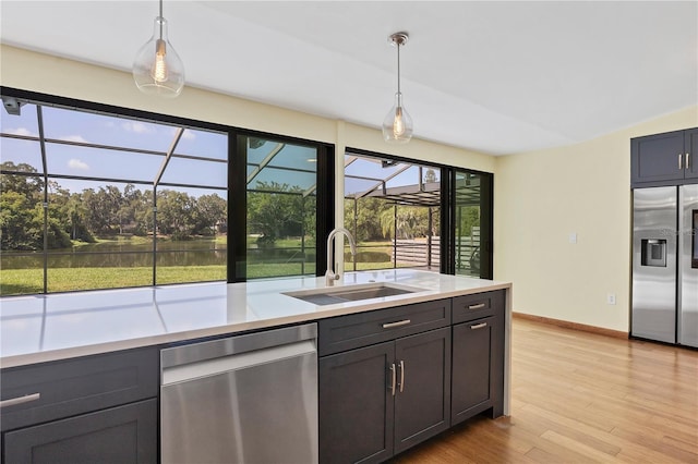 kitchen with appliances with stainless steel finishes, decorative light fixtures, light hardwood / wood-style floors, and sink