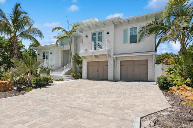 view of front facade with a garage, a balcony, and french doors