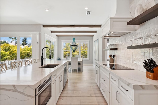 kitchen featuring backsplash, stainless steel appliances, light stone counters, and sink