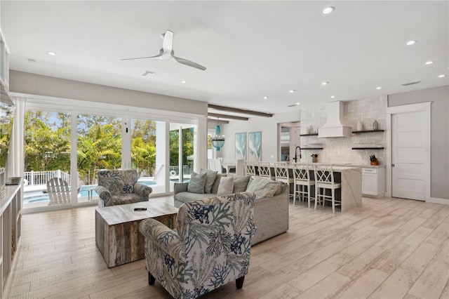 living room featuring ceiling fan, light hardwood / wood-style flooring, and sink