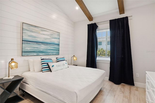 bedroom with vaulted ceiling with beams, light hardwood / wood-style floors, and wooden walls