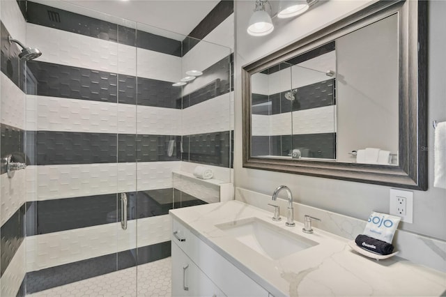 bathroom featuring a shower with door and vanity