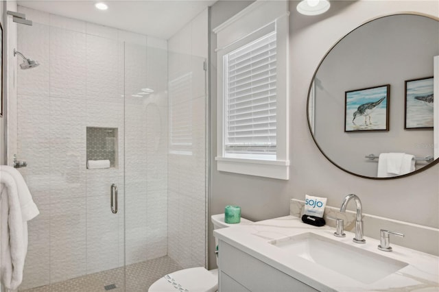 bathroom featuring vanity, toilet, and a shower with door