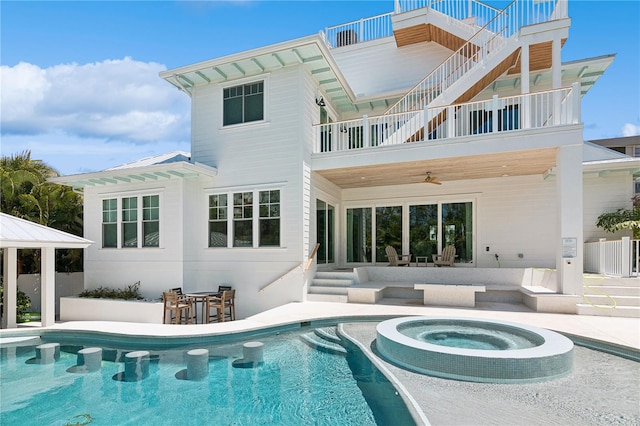 back of house with ceiling fan, a pool with hot tub, a patio area, and an outdoor bar