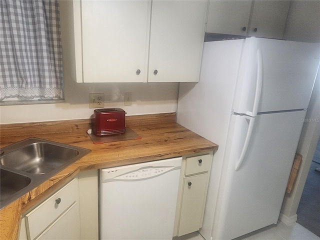 kitchen with white appliances, sink, butcher block countertops, light tile patterned flooring, and white cabinetry