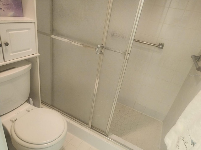 bathroom featuring tile patterned floors, toilet, and a shower with shower door