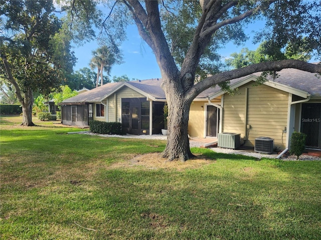 exterior space with central AC, a sunroom, and a yard