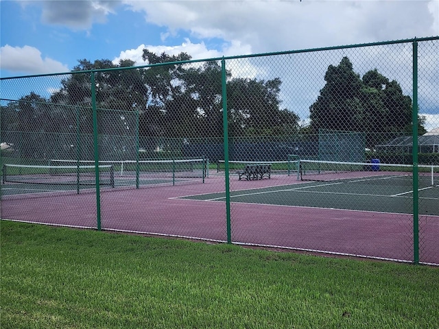 view of tennis court featuring a yard