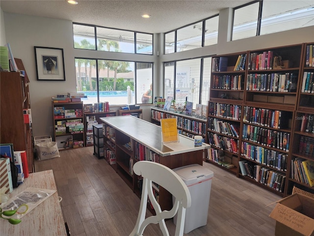 office space featuring a towering ceiling, wood-type flooring, and a textured ceiling