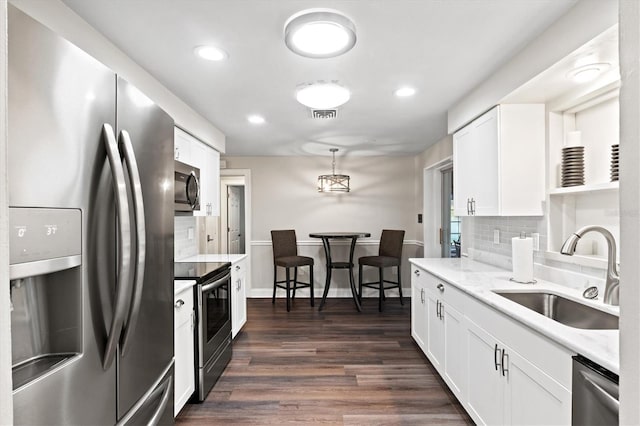 kitchen featuring white cabinets, stainless steel appliances, backsplash, dark wood-type flooring, and sink