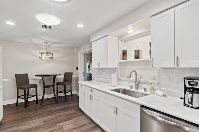 kitchen featuring decorative light fixtures, dark hardwood / wood-style floors, backsplash, stainless steel dishwasher, and sink