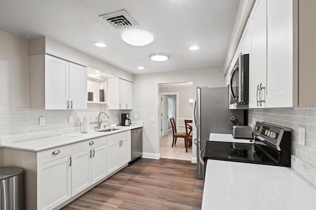 kitchen featuring stainless steel appliances, backsplash, hardwood / wood-style flooring, white cabinets, and sink