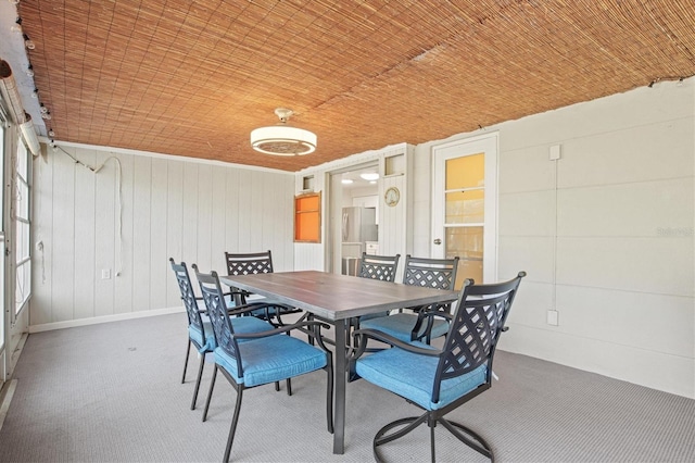 carpeted dining room featuring wooden ceiling