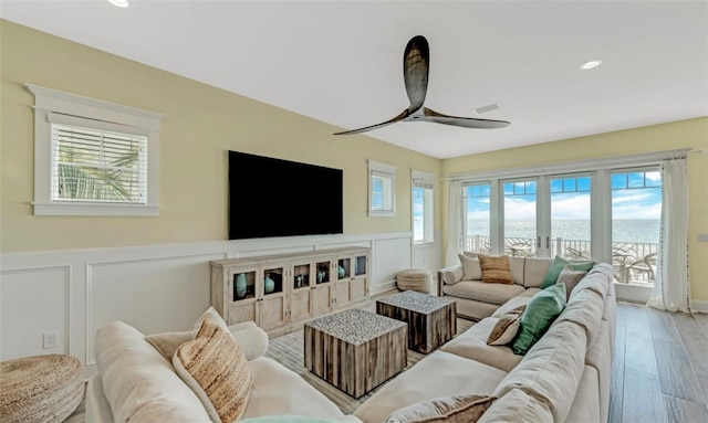 living room featuring ceiling fan, wood-type flooring, and a wealth of natural light