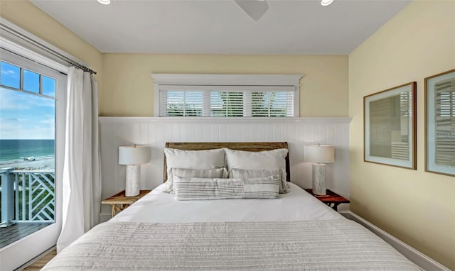 bedroom with a water view, multiple windows, and hardwood / wood-style flooring