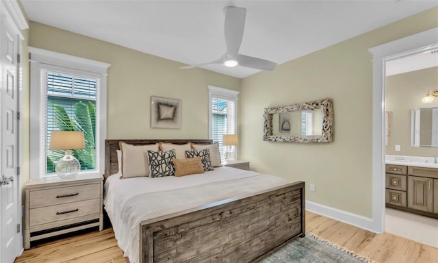 bedroom with light wood-type flooring, connected bathroom, and multiple windows