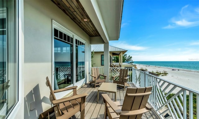 balcony featuring a view of the beach and a water view