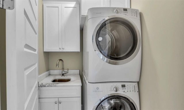 washroom featuring stacked washer / dryer, sink, and cabinets