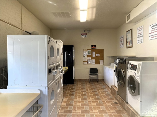 laundry room featuring a textured ceiling, washer and clothes dryer, and stacked washer / drying machine