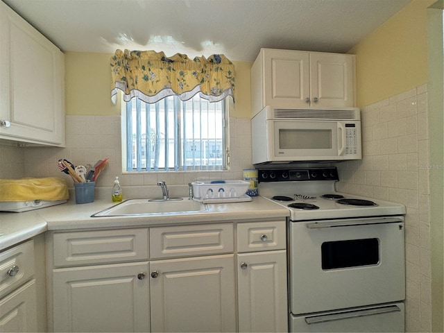 kitchen with white cabinets, decorative backsplash, white appliances, and sink