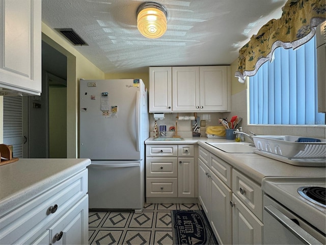 kitchen featuring white cabinetry, sink, backsplash, white fridge, and light tile patterned floors