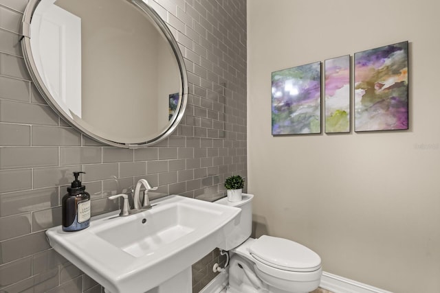 bathroom with sink, tile walls, and toilet