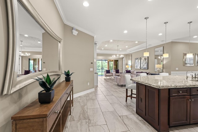 kitchen featuring light stone countertops, dark brown cabinetry, a chandelier, and ornamental molding