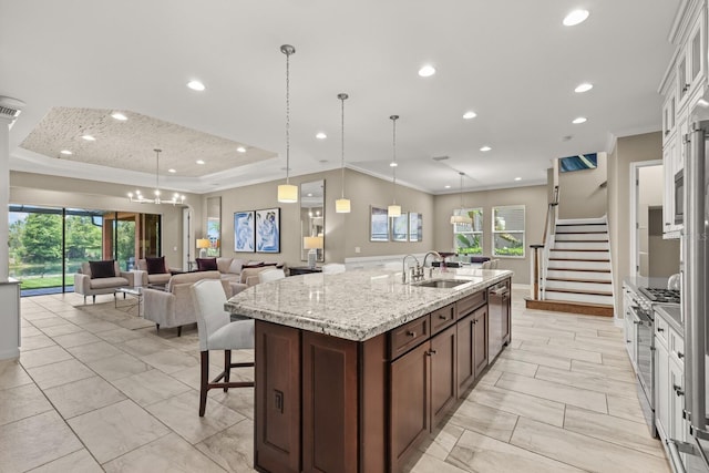 kitchen featuring sink, an island with sink, pendant lighting, white cabinets, and appliances with stainless steel finishes