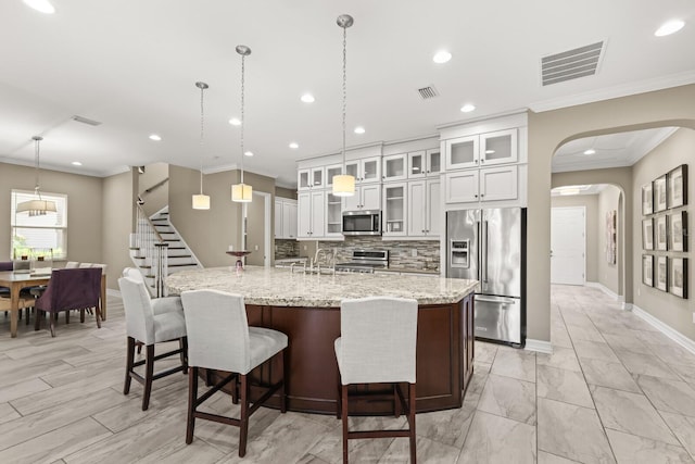 kitchen featuring stainless steel appliances, white cabinetry, and hanging light fixtures