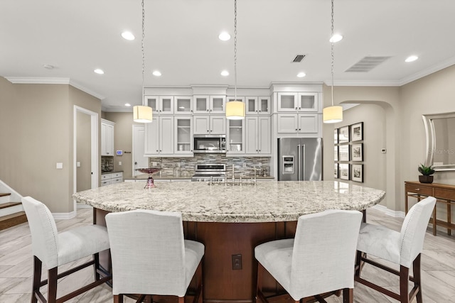 kitchen with a kitchen breakfast bar, a large island with sink, crown molding, decorative light fixtures, and appliances with stainless steel finishes