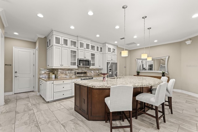 kitchen featuring hanging light fixtures, a center island with sink, white cabinets, and stainless steel appliances