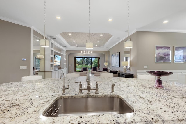 kitchen featuring crown molding, sink, light stone countertops, a tray ceiling, and decorative light fixtures