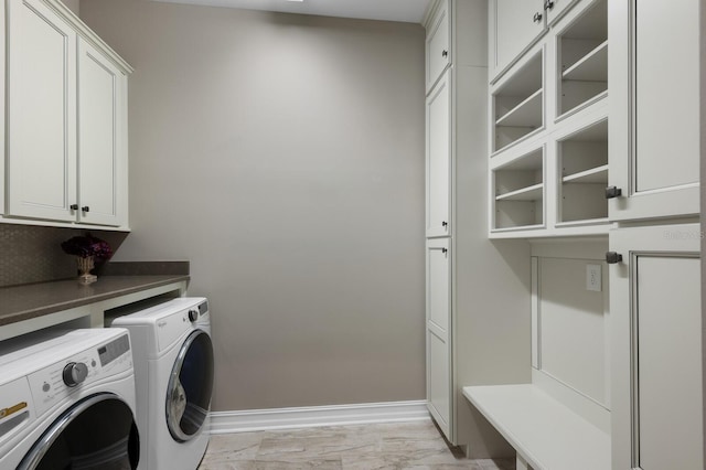 clothes washing area featuring cabinets and separate washer and dryer