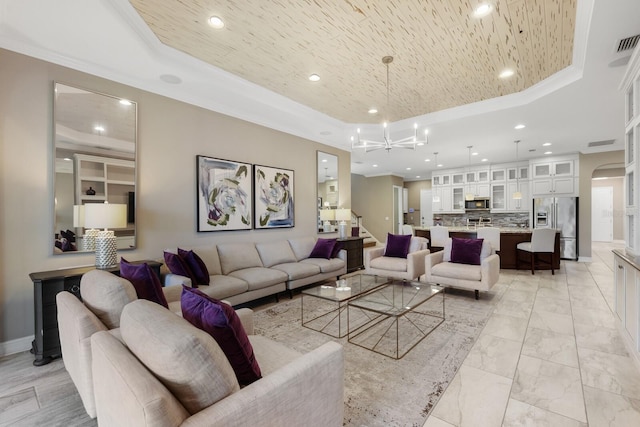 living room with a tray ceiling, crown molding, and a notable chandelier