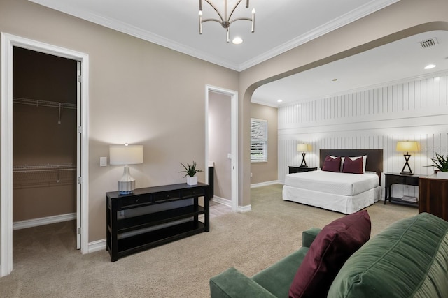 carpeted bedroom with a walk in closet, ornamental molding, and a closet