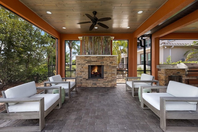 view of patio with an outdoor living space with a fireplace and ceiling fan