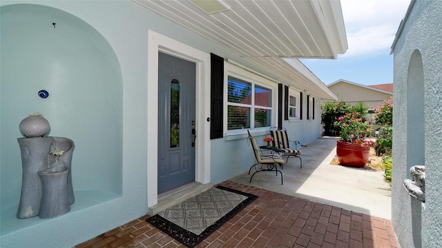 doorway to property featuring covered porch and stucco siding